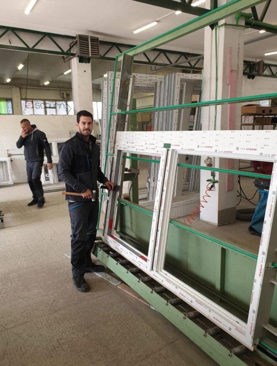 Mitarbeiter mit einem Fensterrahmen in der Fertigung